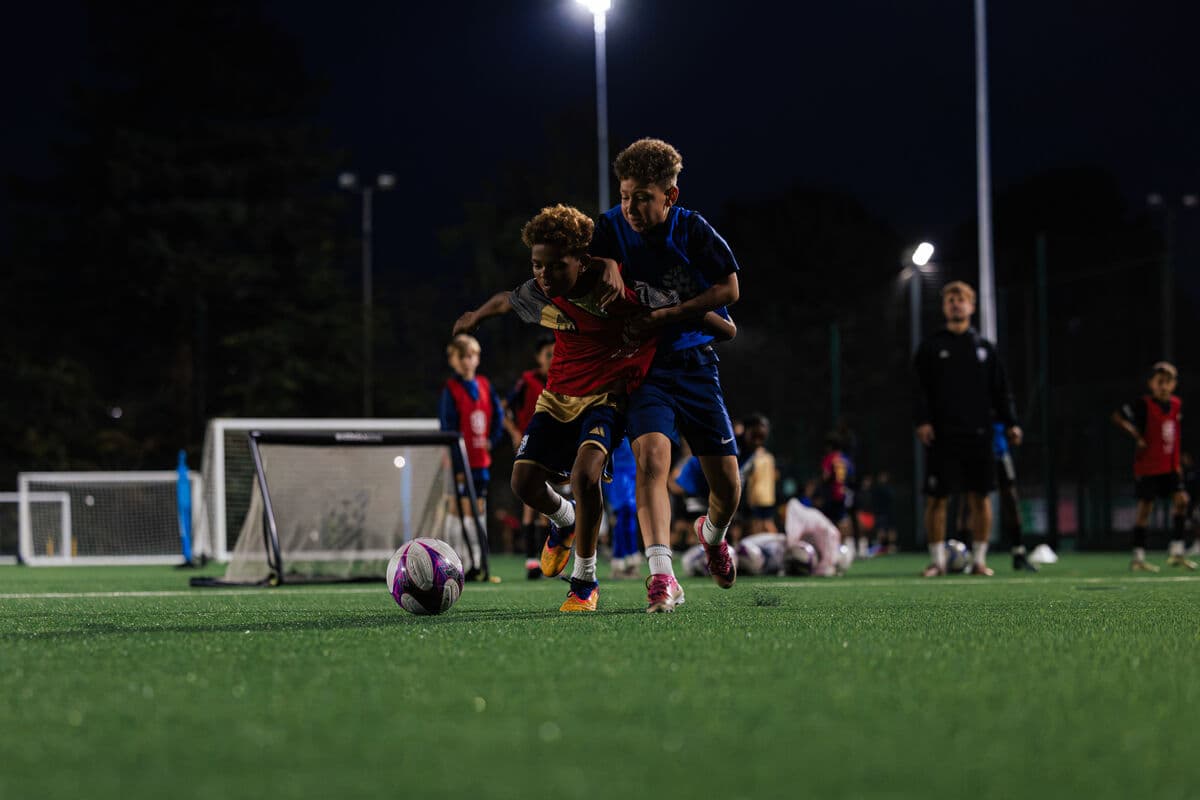 Two players battling for the ball, one shielding it from the other
