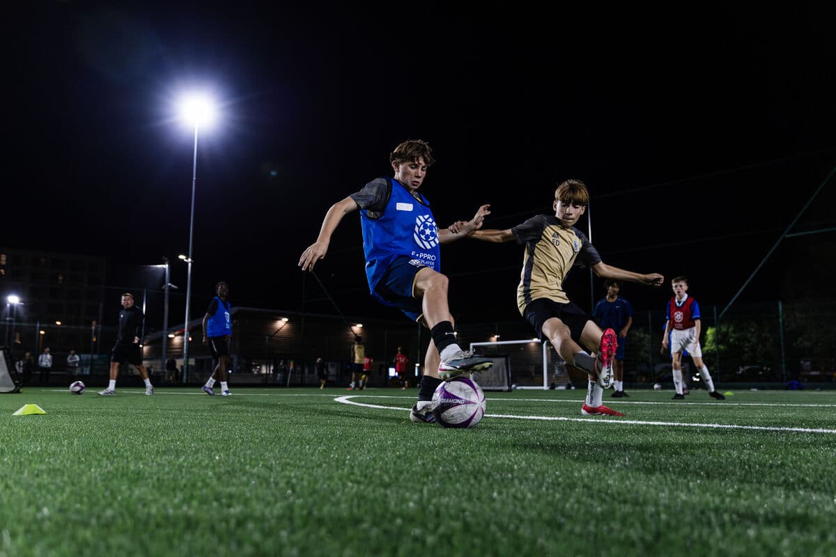 An E-PPRO player taking on a defender 1v1 under floodlights