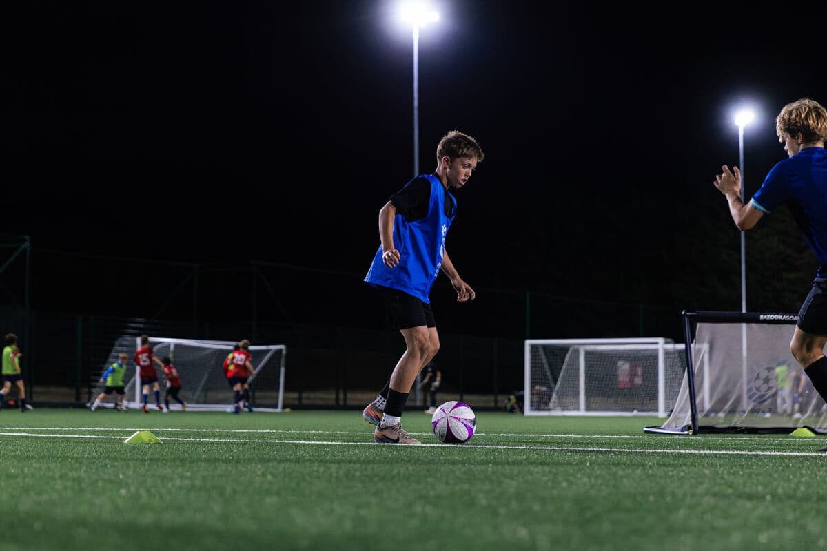 A player shaping to strike the ball on a floodlit pitch